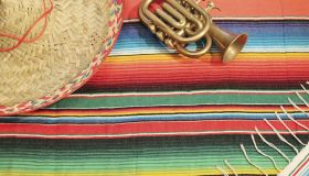 Traditional Mexican fiesta poncho rug in bright colors with sombrero background with copy space