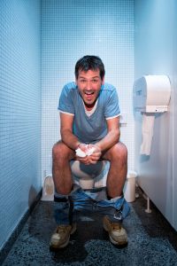 happy man sitting in public restroom