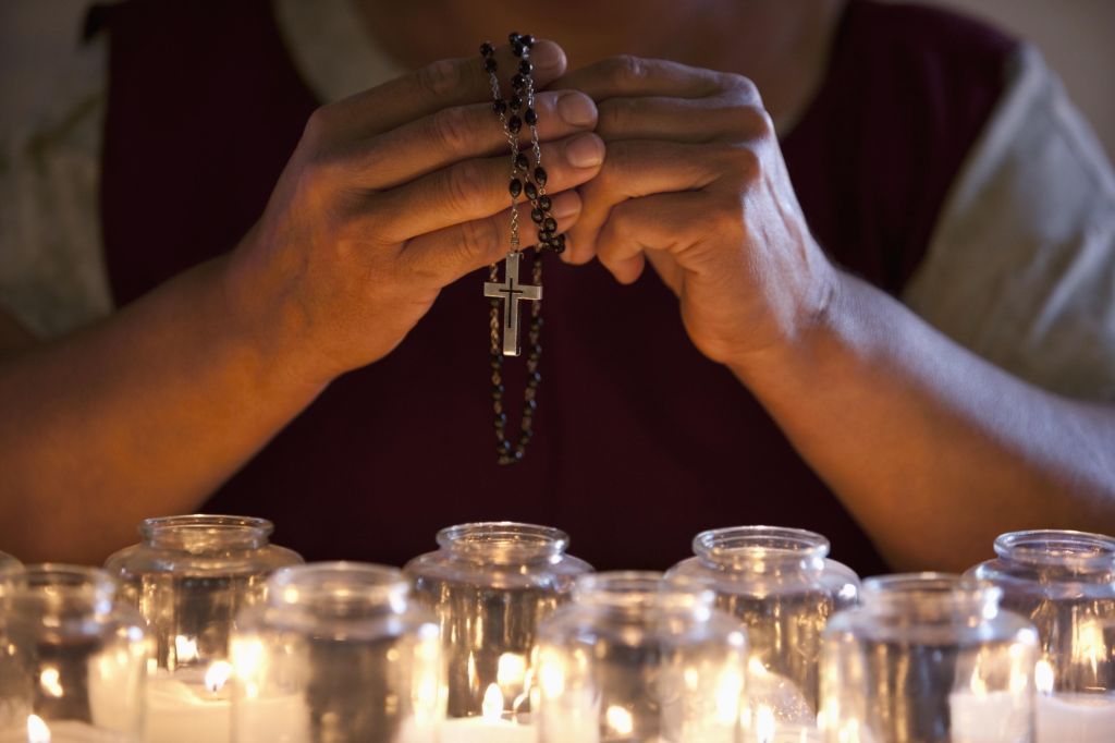 Hands holding prayer beads over candles