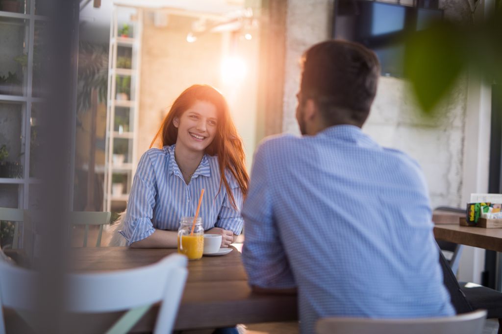 Young smiling redhead woman talking to her boyfriend in a cafe.