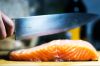 Kitchen knife cutting fresh salmon steak