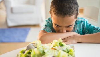 Mixed race boy refusing to eat salad