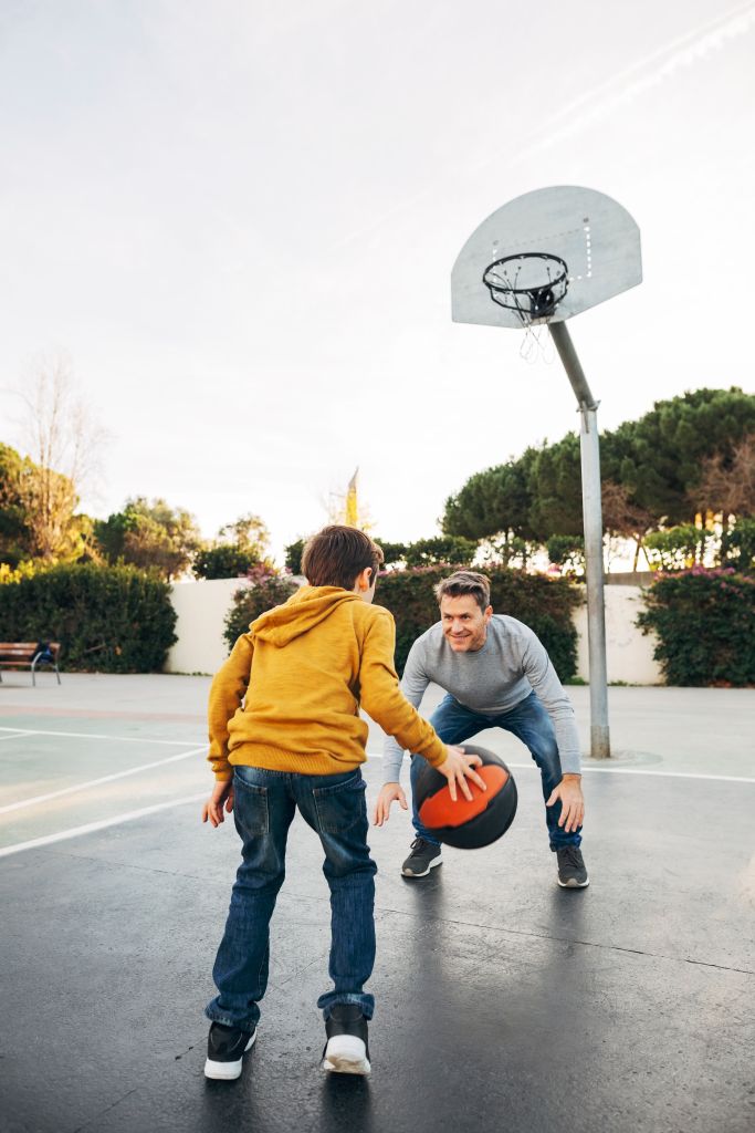 Father and son playing basketball on an outdoor court