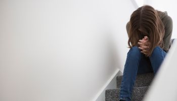 Teenage girl sitting on stairs with head down in despair