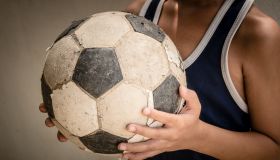 Midsection Of Boy Standing With Soccer Ball Against Wall
