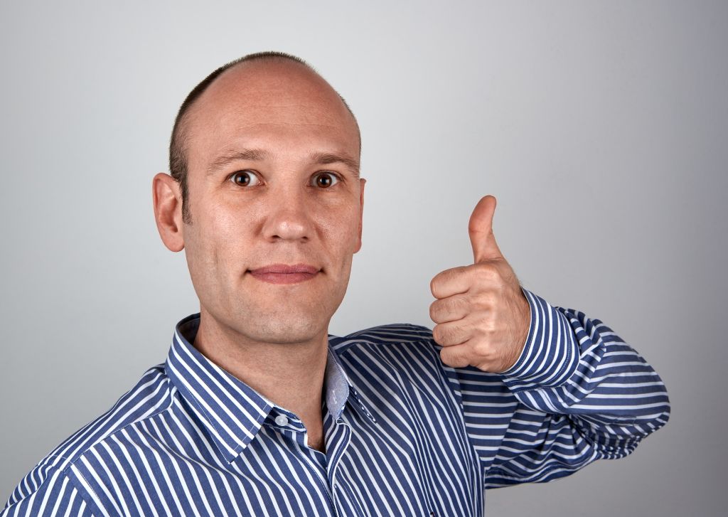 Portrait Of Mature Man Showing Thumbs Up Against Gray Background