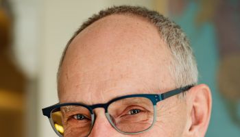 Portrait of bald senior man with glasses smiling.