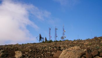 Low Angle View Of Repeater Towers And Satellite Dish On Field