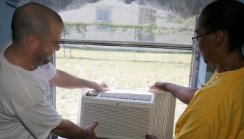 A man and woman installing an AC unit on National Rebuilding Day at Coconut Grove
