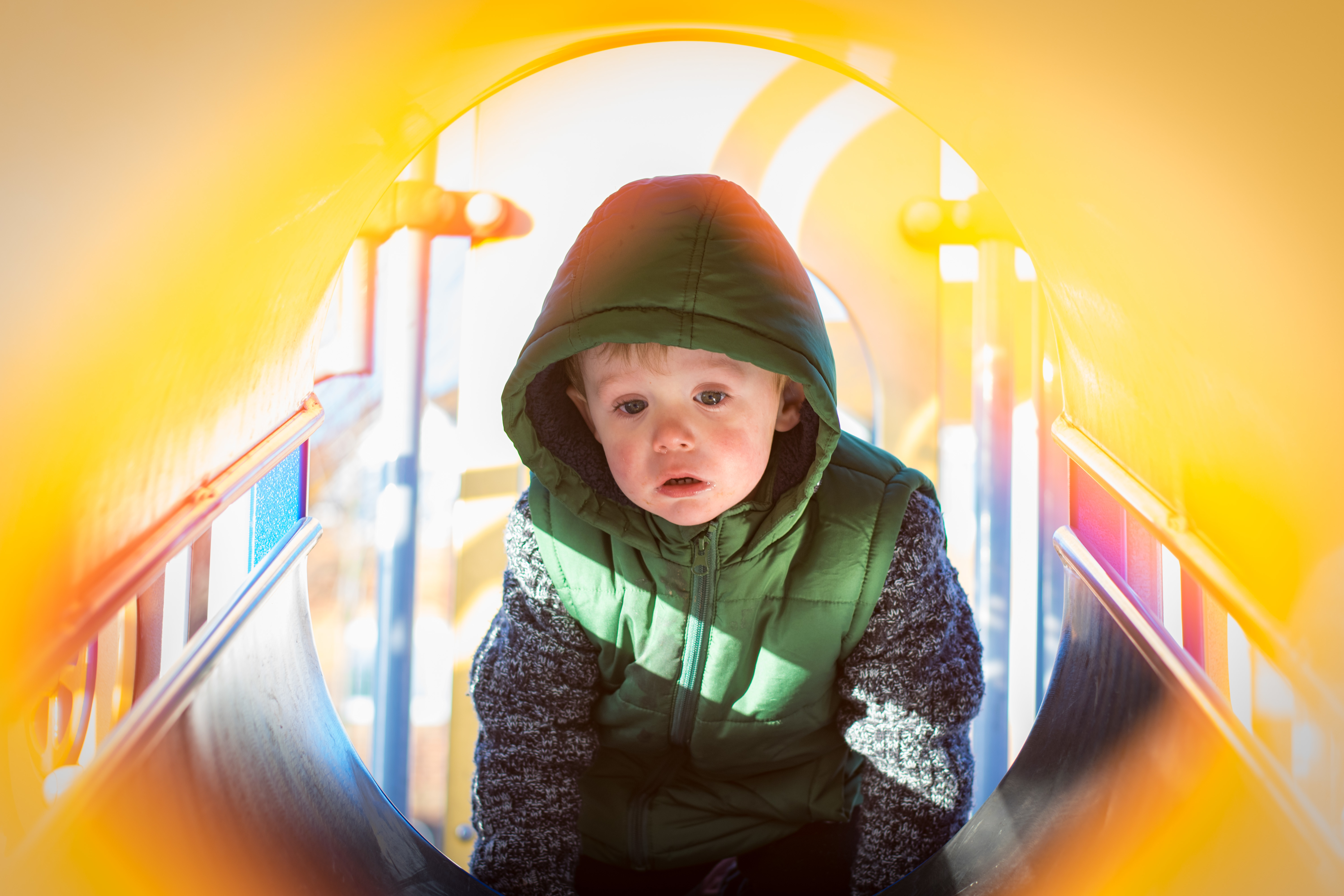 Serious Boy Sitting On Slide At Playground