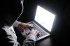 hooded hacker stealing data from laptop