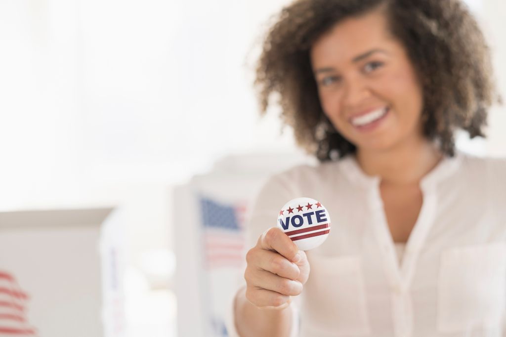 Young woman holding voting badge and smiling