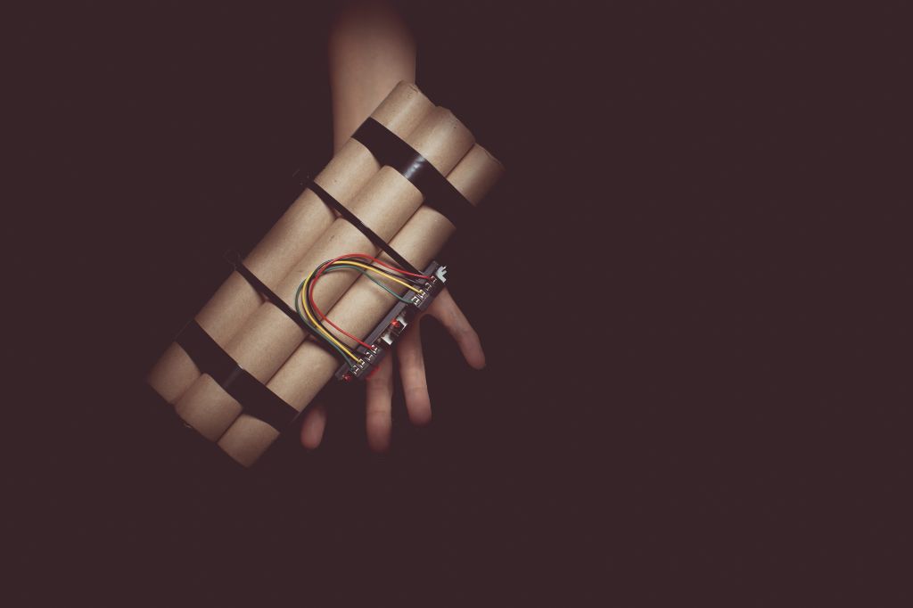 Cropped Hand Holding Bomb Over Black Background