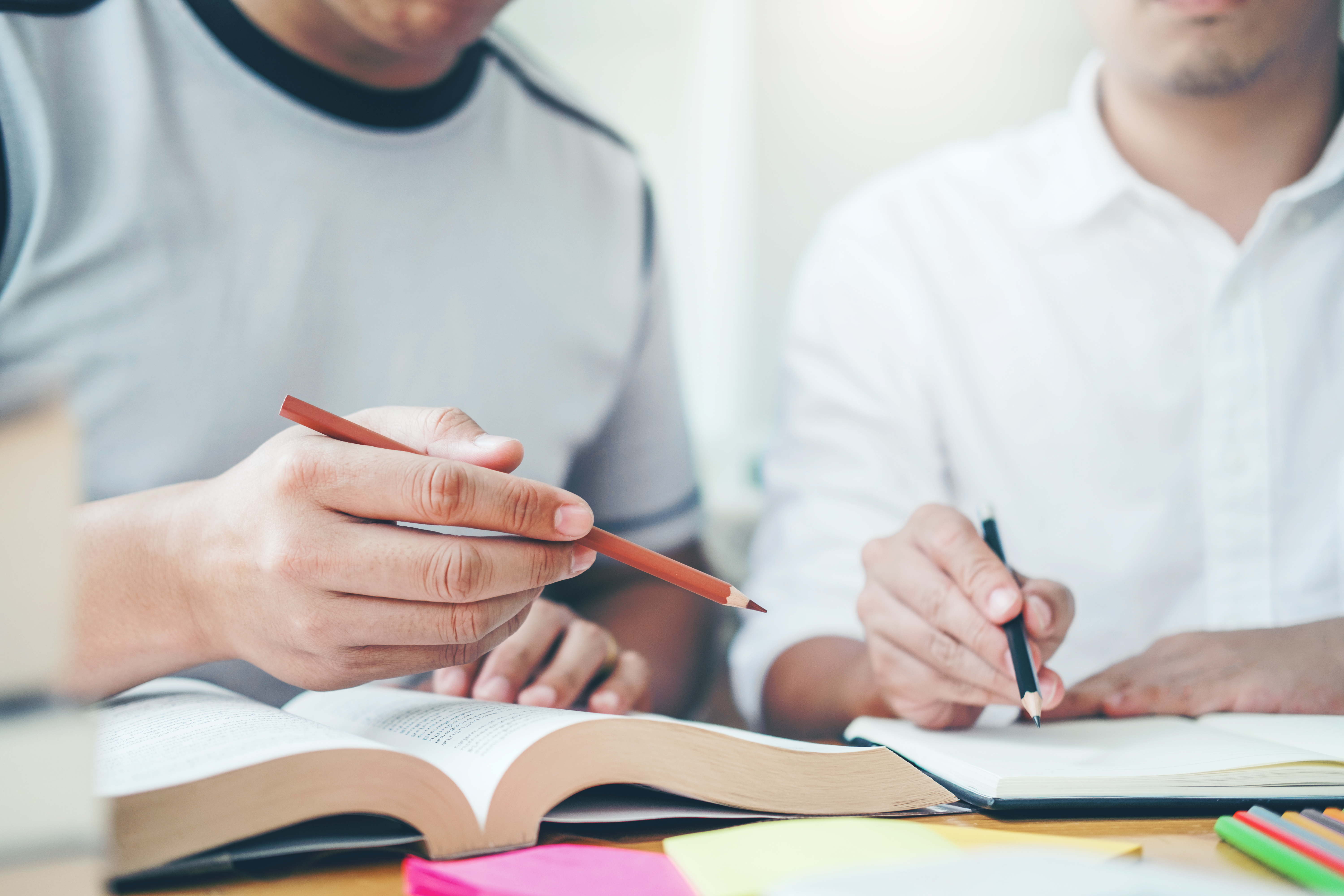 Midsection Of Students Studying On Desk
