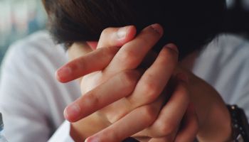 Close-Up Of Worried Woman With Hands Clasped