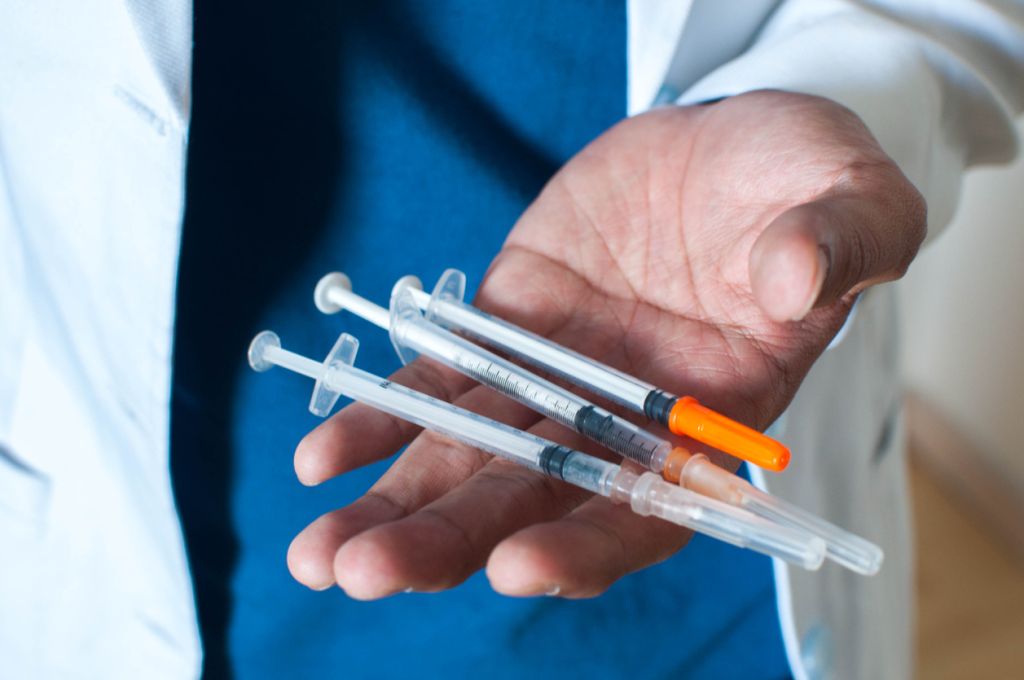 A close-up of a doctor holding syringes