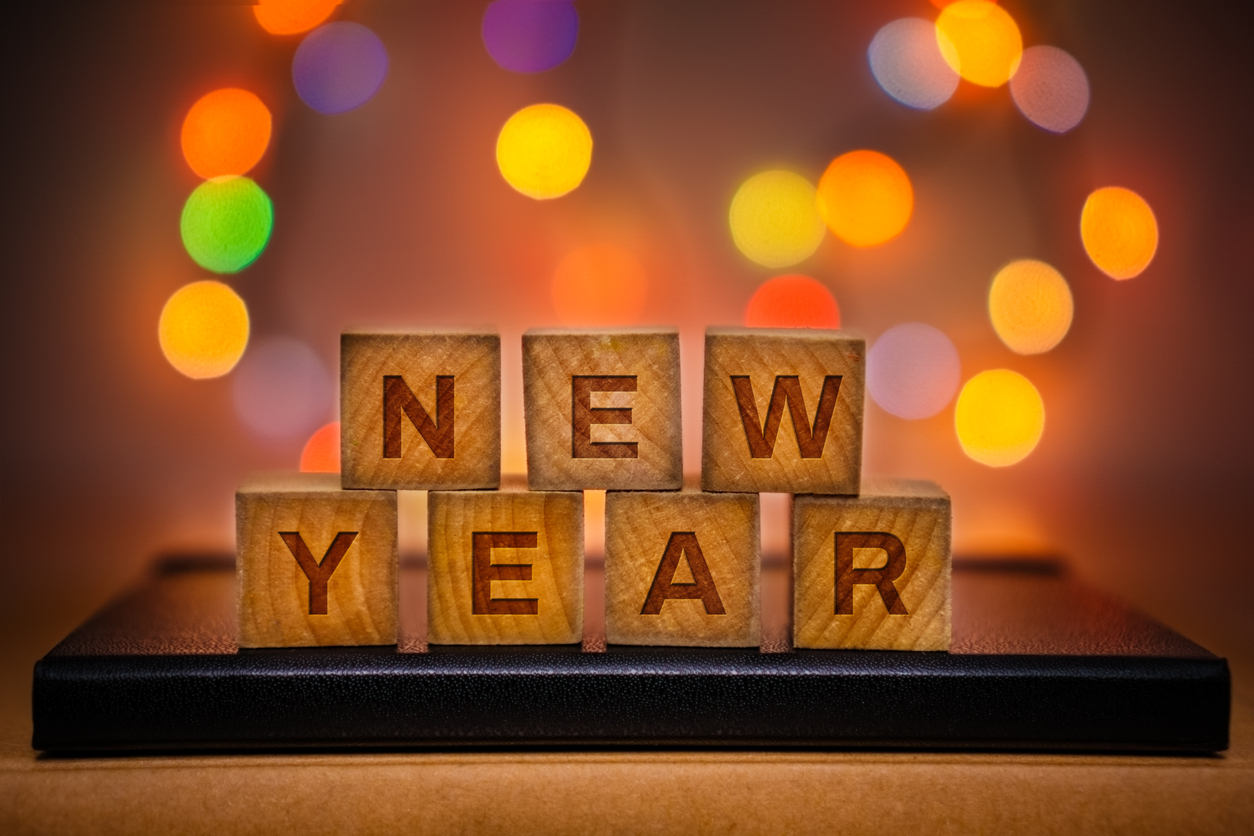 New Year Text on Wood Block Against Abstract Colorful Illuminated Defocused Bokeh Lights Background.