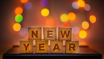 New Year Text on Wood Block Against Abstract Colorful Illuminated Defocused Bokeh Lights Background.