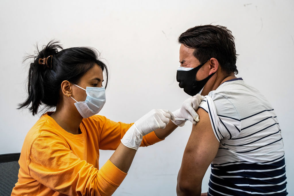 Nepali man reacts while taking his first jab of China-made...