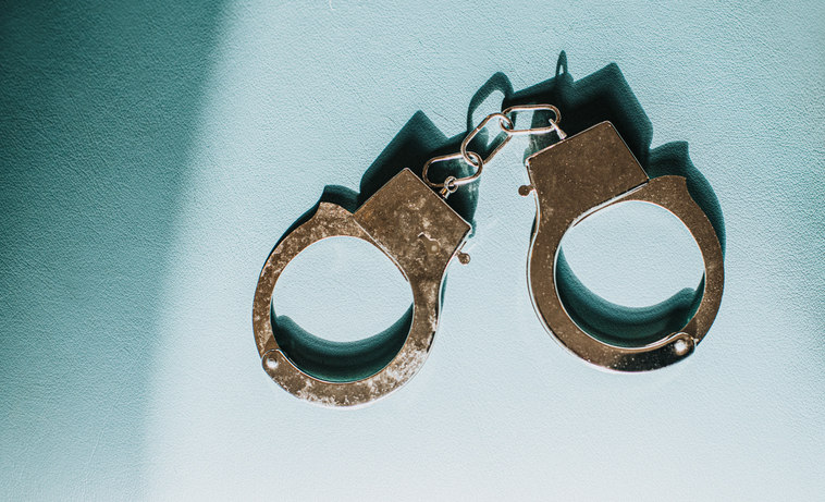 Simple Conceptual Image of Silver Handcuffs on Blue Surface