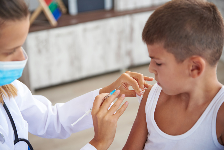 a pediatrician vaccinates a little boy in a pediatric clinic