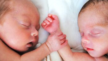 Newborn Premature Twins holding hands