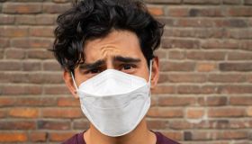 Young Latino man wearing a face mask and looking very confused and frustrated at the camera