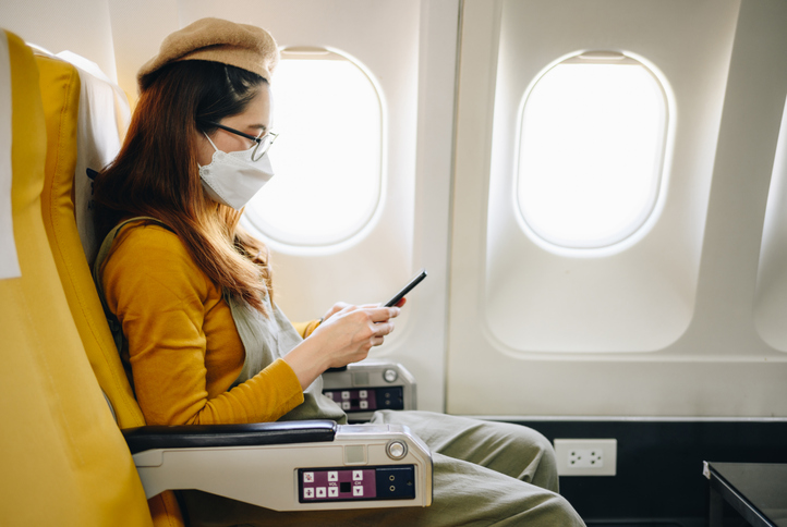 Asian passenger wearing face mask while seating on plane. New normal lifestyle of people after covid-19 pandemic.