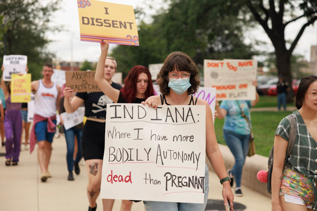 A woman carries a placard saying 'Indiana where I have more...
