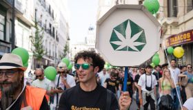 A pro-cannabis protester holds a sign with a marijuana...