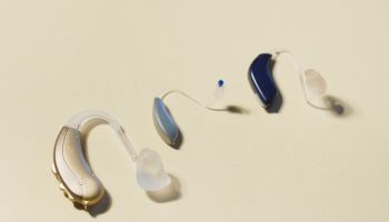 High angle view of various hearing aids on yellow table