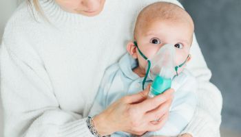 Baby getting breathing treatment from mother