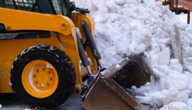 Heavy duty earth mover cleaning snow off the sidewalks after blizzard.