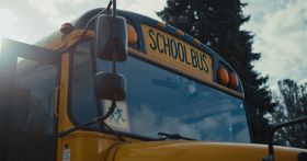 Front view academic bus window with warning sign yellow red headlights close up.