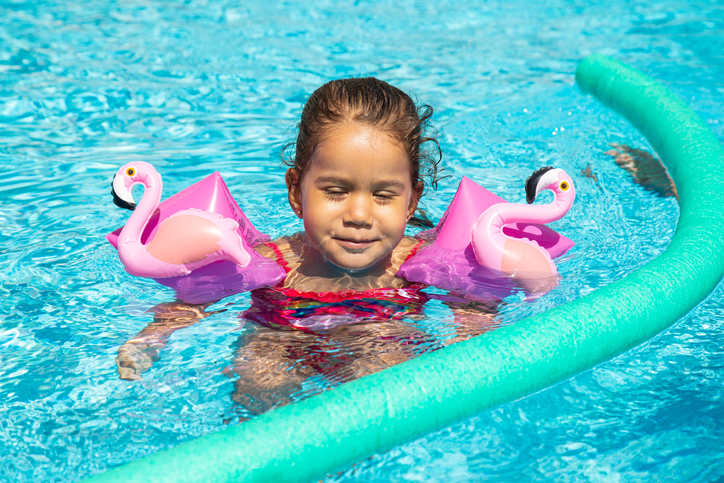 Little girl enjoying herself in the swimming pool with floats,Madrid,Spain