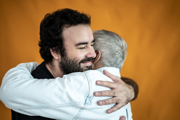 Father and son hugging each other on an orange background