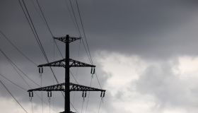 High voltage tower silhouette with electrical wires on storm sky background with dark clouds
