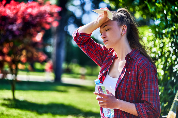 Young tired woman suffering from hot weather outdoors in a summer day