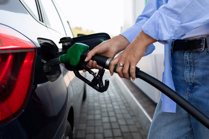 Woman refuels a car with gasoline using a gas gun