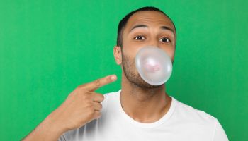 Portrait of man blowing bubble gum on green background