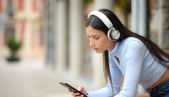 Woman listening audio with headphones and phone