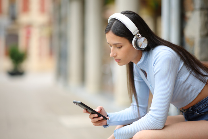 Woman listening audio with headphones and phone