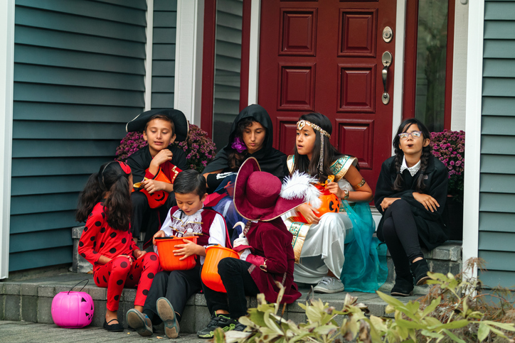 Children In Costumes Enjoying Treats On Steps