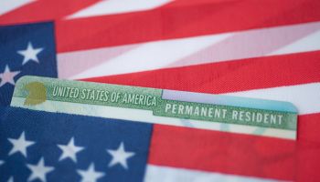 Permanent Resident Green card of United states covered in flag of USA.