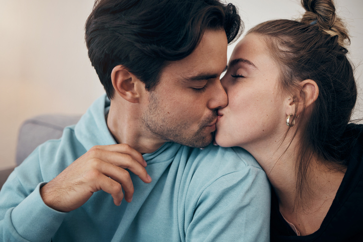 Couple, relax and kiss on sofa with love in home, living room or house with happy, partnership or marriage. Romantic, people and bonding with man and woman in affection for support and care together