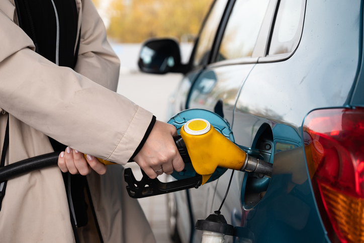 Pumping gas at the gas pump. The woman refuels the car. A woman at a gas station. A woman refuels a car with gasoline at a gas station. Fuel injection into the tank. Detail of a woman filling a car with diesel fuel
