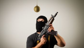 Man in mask with gun and Christmas toy.