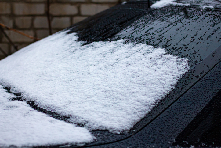 Drops of melted snow on an old black European car