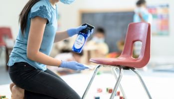 Teacher Sanitizing Classroom Chair Stock Photo