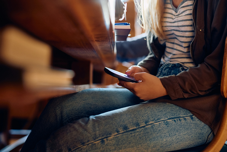 Close up of student using cell phone during a class at school.